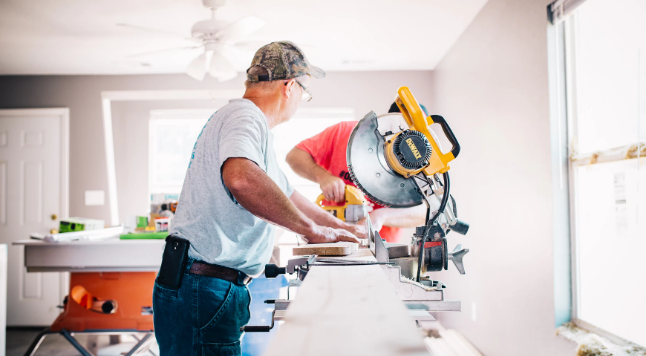 Man met houten plank en afkortzaag